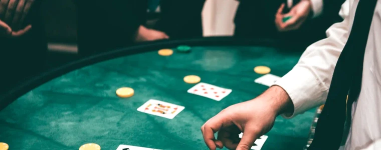 Bàn baccarat màu xanh nhìn từ trên xuống với các lá bài và ba ô đặt cược Banker, Player, Tie cùng vài chồng phỉnh.